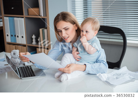 Beaming mother working at table with kid 36530832