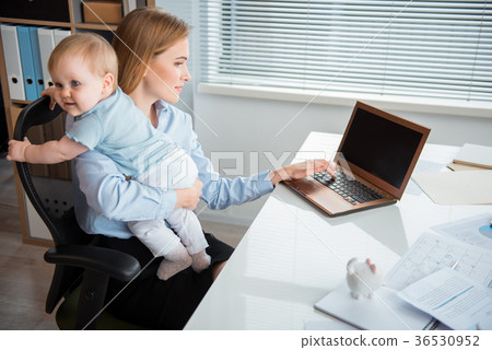 Serious mother with baby having job Serious mother with baby having job 36530952
