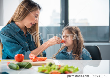 Asian mother feeding her child by tomato Asian mother feeding her child by tomato 36531150