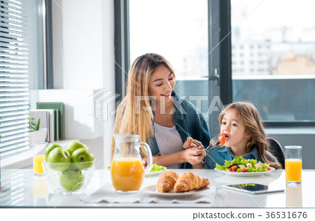 Happy asian woman helping her daughter to eat Happy asian woman helping her daughter to eat 36531676
