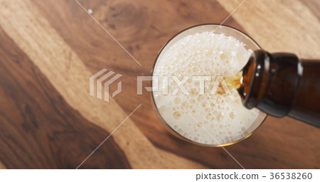 top view pouring lager beer from bottle into glass top view pouring lager beer from bottle into glass 36538260