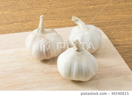 Three Fresh Garlic Bulbs on Wooden Cutting Board 36540815