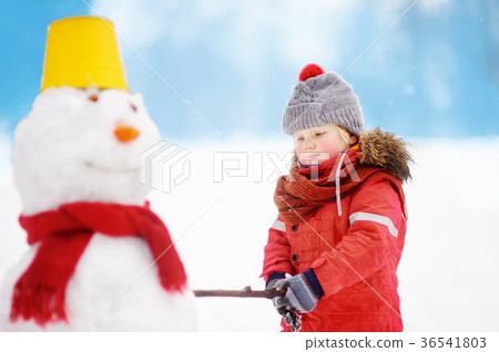 Little boy in red winter clothes having fun with snowman in snowy park Little boy in red winter clothes having fun with snowman in snowy park 36541803