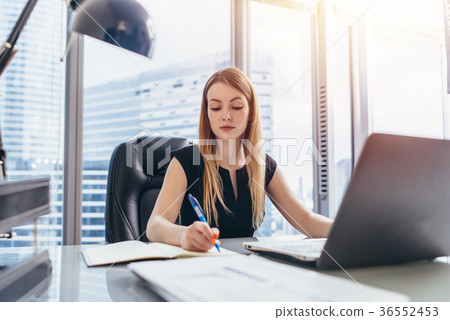 Female chief executive sitting at her desk taking Female chief executive sitting at her desk taking 36552453