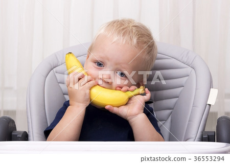 Cute one year old toddler eating a banana and Cute one year old toddler eating a banana and 36553294