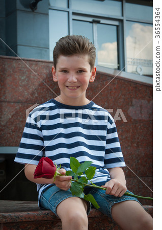 boy holding a rose and smiling. the concept of boy holding a rose and smiling. the concept of 36554364