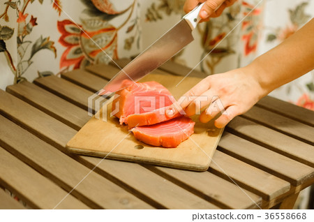 Woman cutting fresh salmon fillet on wooden board 36558668