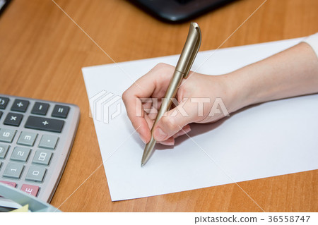 Close up hand with pen writes on paper on desk Close up hand with pen writes on paper on desk 36558747