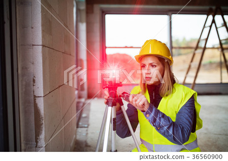 Young woman worker with laser on the building site Young woman worker with laser on the building site 36560900