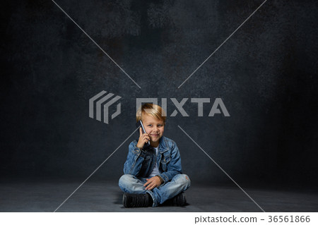 Little boy sitting with smartphone in studio Little boy sitting with smartphone in studio 36561866