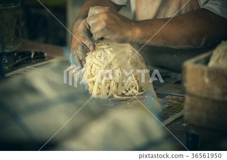 A man packs handmade noodles on the local market  36561950