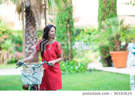 Young happy woman on bike in tropical resort 36583624