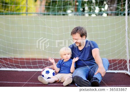 Little boy and his middle age father having fun playing a soccer/football game on summer day Little boy and his middle age father having fun playing a soccer/football game on summer day 36583867