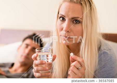 Worried woman taking a pill before sleep at night Worried woman taking a pill before sleep at night 36587085