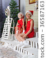 happy mom and daughter in Christmas costumes are sitting under snow 36587163