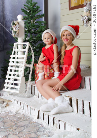 happy mom and daughter in Christmas costumes are sitting under snow happy mom and daughter in Christmas costumes are sitting under snow 36587163