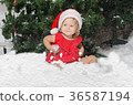 smiling girl in santa costume sits on snow 36587194