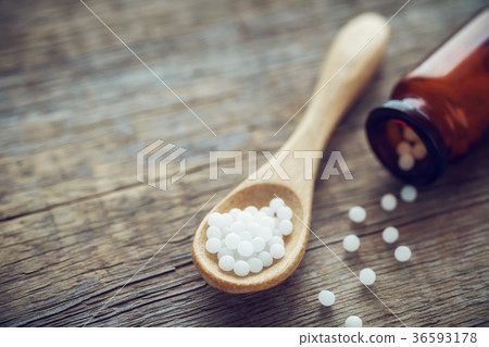 Wooden spoon of homeopathic globules and bottle 36593178
