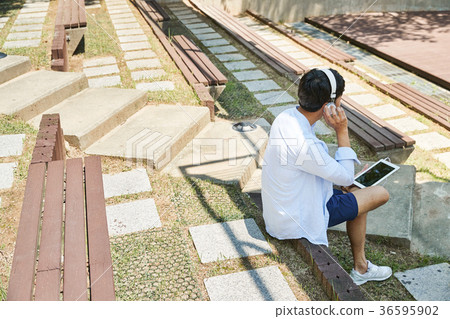 Young guy take a relax in park, sit on green grass and walking in around. 041 36595902