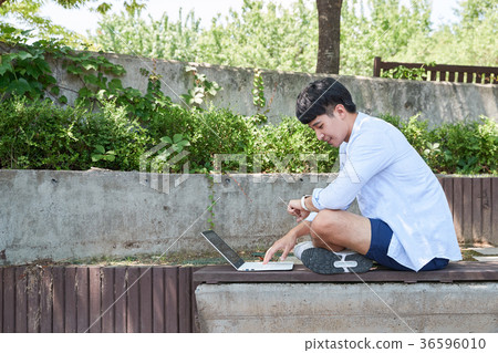 Young guy take a relax in park, sit on green grass and walking in around. 068 36596010