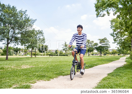 Young guy take a relax in park, sit on green grass and walking in around. 095 36596084