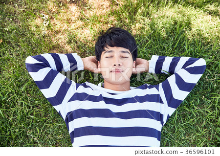 Young guy take a relax in park, sit on green grass and walking in around. 101 36596101