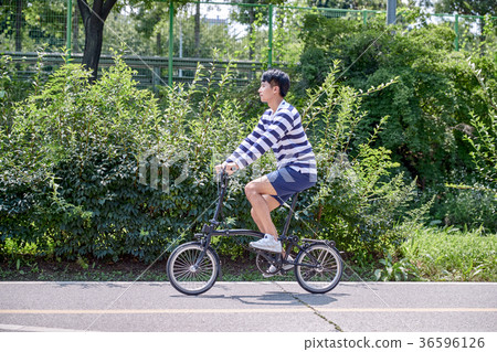 Young guy take a relax in park, sit on green grass and walking in around. 104 36596126