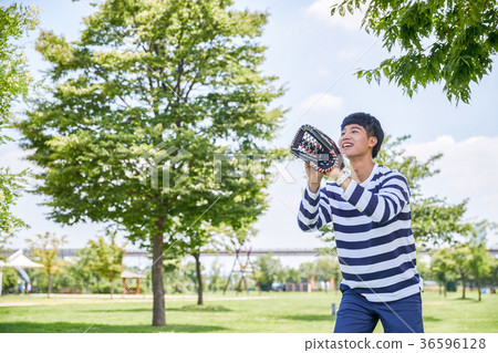 Young guy take a relax in park, sit on green grass and walking in around. 114 36596128