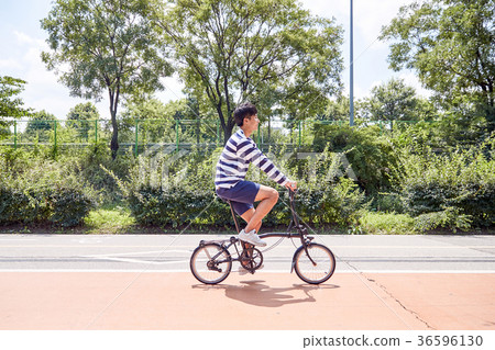 Young guy take a relax in park, sit on green grass and walking in around. 107 36596130