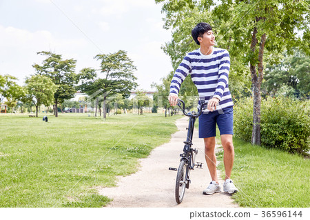 Young guy take a relax in park, sit on green grass and walking in around. 121 36596144