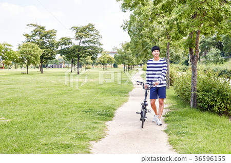 Young guy take a relax in park, sit on green grass and walking in around. 125 36596155