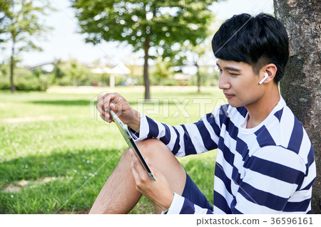 Young guy take a relax in park, sit on green grass and walking in around. 133 36596161