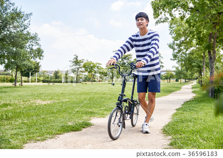 Young guy take a relax in park, sit on green grass and walking in around. 137 36596183