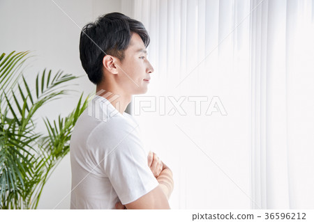 Young guy standing at the front of window with bright sunlight. 151 36596212