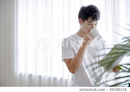 Young guy standing at the front of window with bright sunlight. 190 36596236