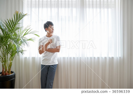 Young guy standing at the front of window with bright sunlight. 194 36596339