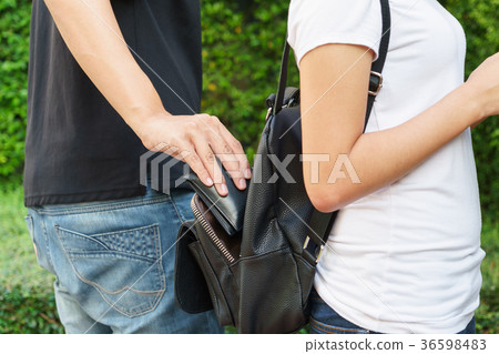 Thief trying to steal the wallet in the backpack 36598483