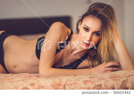 Attractive blonde woman in black lingerie posing on her bed Attractive blonde woman in black lingerie posing on her bed 36603482