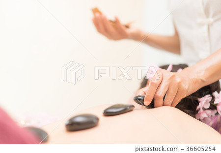 Spa Therapist is placing hot stone on woman back Spa Therapist is placing hot stone on woman back 36605254