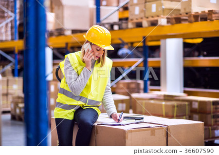 Woman warehouse worker with smartphone. Woman warehouse worker with smartphone. 36607590