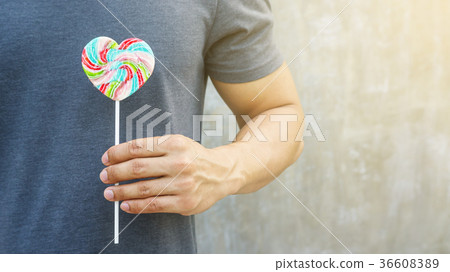Men holding a lollipop on a gray background. Men holding a lollipop on a gray background. 36608389