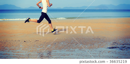 Young fitness woman running on sunrise sandy beach 36635219