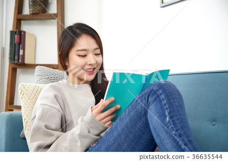 一名年輕女子的日常生活在她20多歲躺在沙發上閱讀生活方式 一名年輕女子的日常生活在她20多歲躺在沙發上閱讀生活方式 36635544