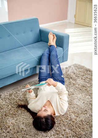 Daily life, life-story work, reading of a young woman who is lying in a carpet and is reading 36635628