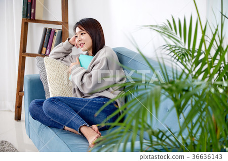 一個女人在她20多歲的閱讀和放鬆在沙發上，生活方式 36636143