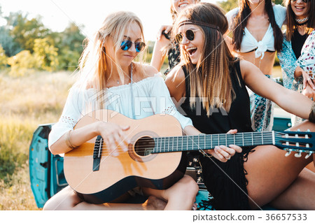Girls are sitting on the trunk with a guitar 36657533