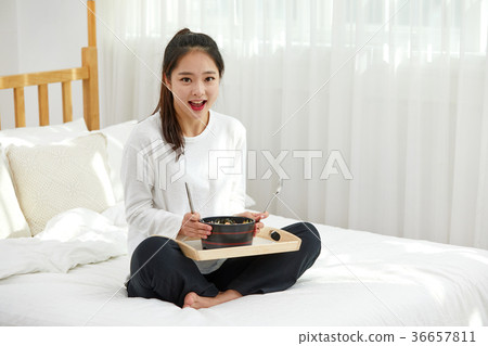 A twenties woman eating in bed A twenties woman eating in bed 36657811