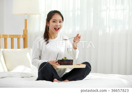 A twenties woman eating in bed A twenties woman eating in bed 36657823