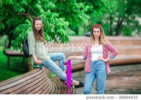 Two hipster girls with skateboard outdoors in the Two hipster girls with skateboard outdoors in the 36664410