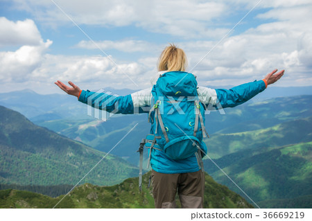 Woman with arms raised on top of mountain looking 36669219